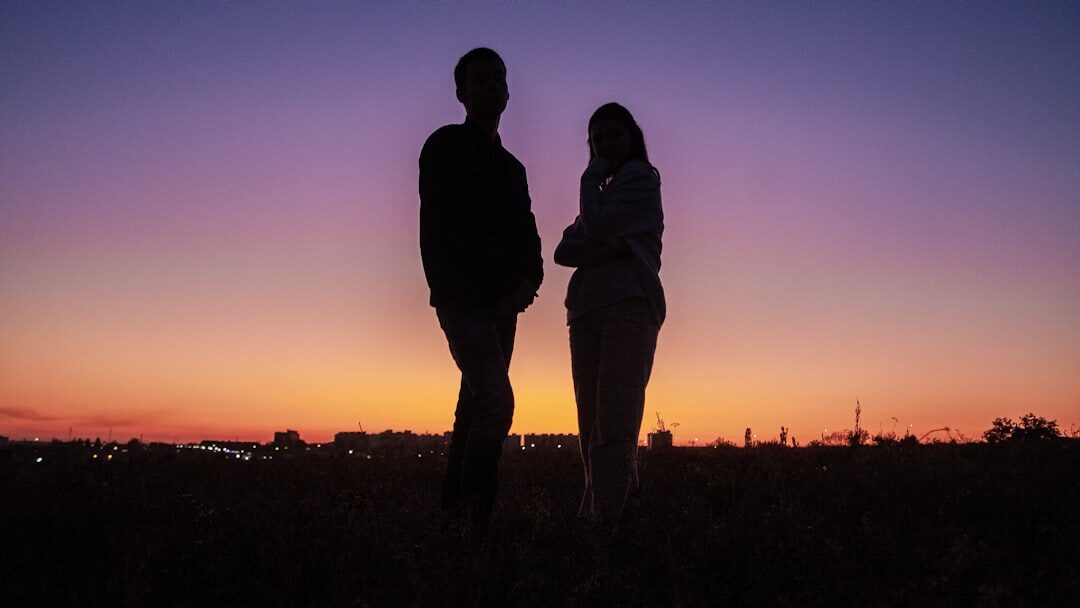Silhouettes of two people talking calmly outdoors at sunset